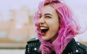 jeune femme aux cheveux roses riant aux éclats