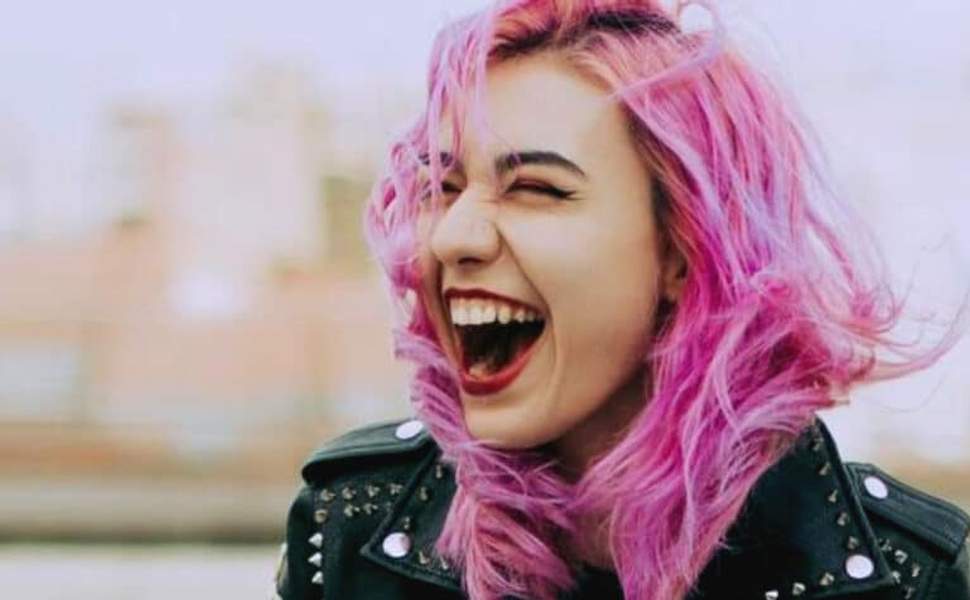 jeune femme aux cheveux roses riant aux éclats