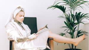 Jeune fille soignant ses cheveux et lisant un magazine