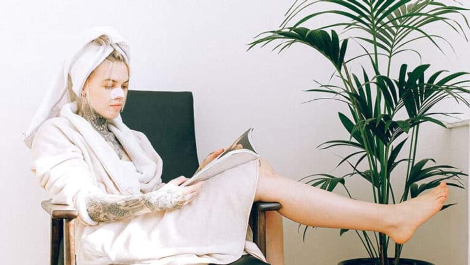 Jeune fille soignant ses cheveux et lisant un magazine