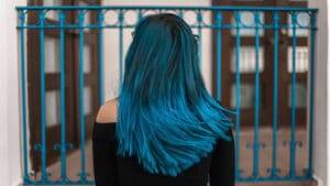 Cheveux longs bleus devant une grille bleu