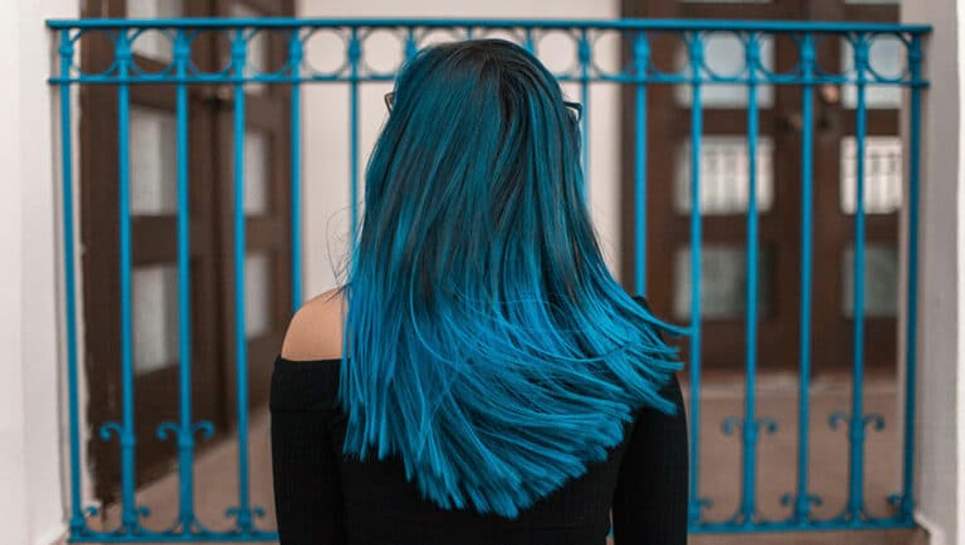 Cheveux longs bleus devant une grille bleu