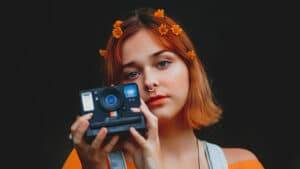 Jeune fille aux cheveux orange avec un appareil photo polaroid